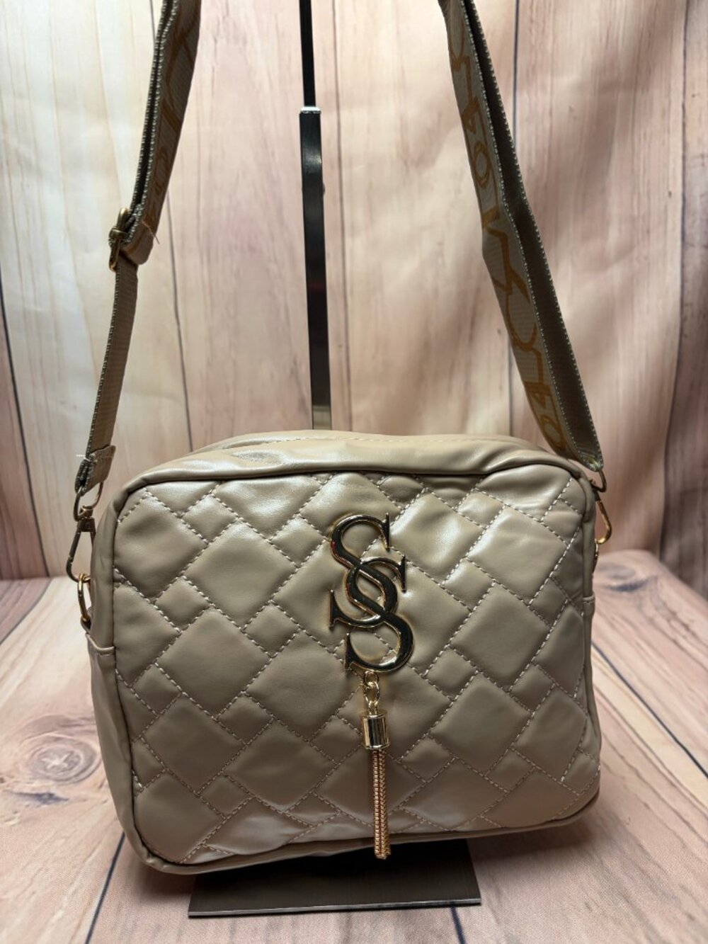 Beige quilted faux-leather crossbody bag features a polished gold monogram